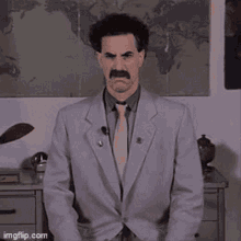 Borat gestures sceptically at a performance claim.